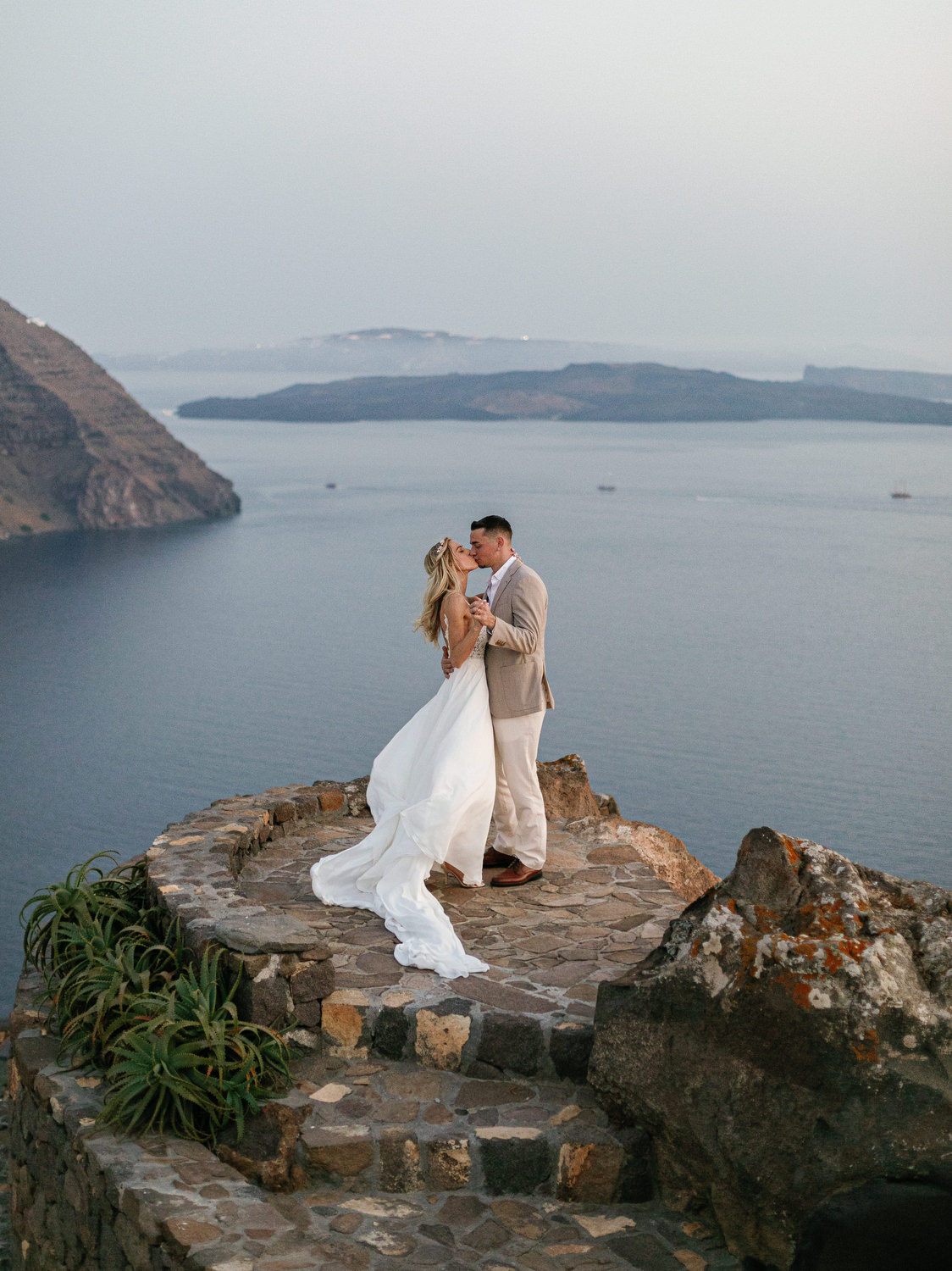 Romantic couple posing with stunning Santorini sunset captured by Santorini wedding photographer