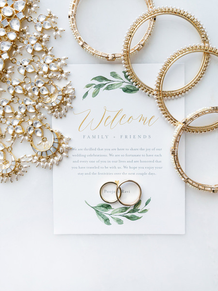 Gold bridal bangles styled beside welcome stationery for a three-day Indian wedding at Grand Hyatt Athens on the Athens Riviera