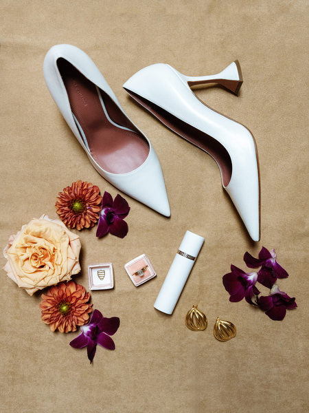 White bridal heels styled with perfume and florals for a sophisticated Italian destination wedding