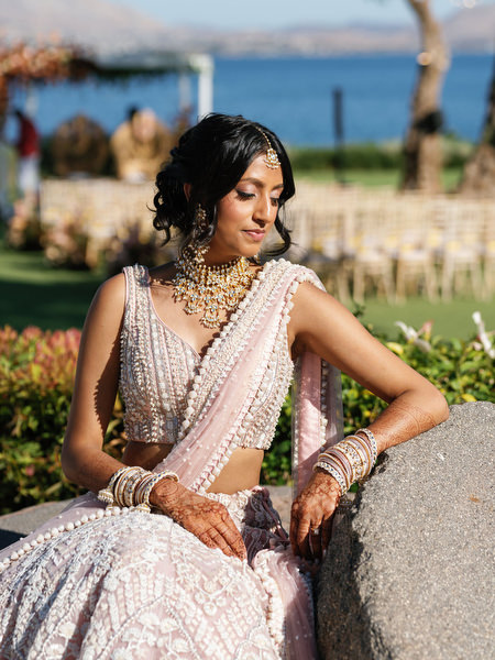 Bride seated with Mediterranean coastline backdrop at an Indian destination wedding in Athens at Island Art & Taste