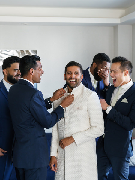 Groom laughing with groomsmen while getting ready for a luxury Indian wedding at Grand Hyatt Athens on the Athens Riviera