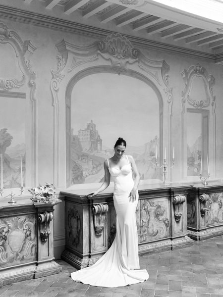 Bride and bridesmaid sharing a quiet moment in an ornate Renaissance interior in Tuscany
