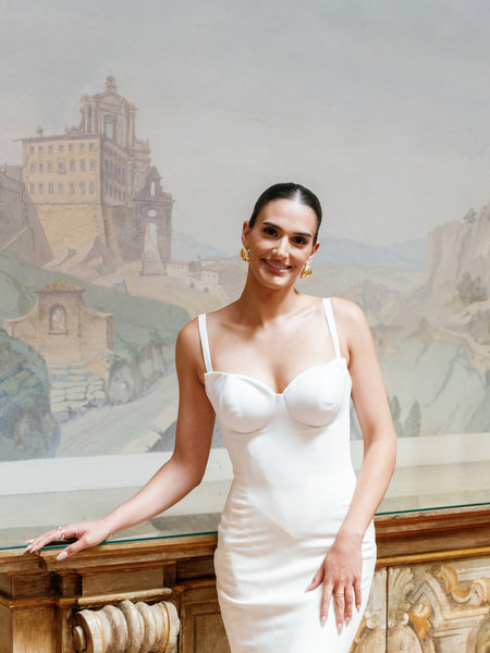 Bride in fitted white wedding gown posing against hand-painted mural walls at La Foce estate