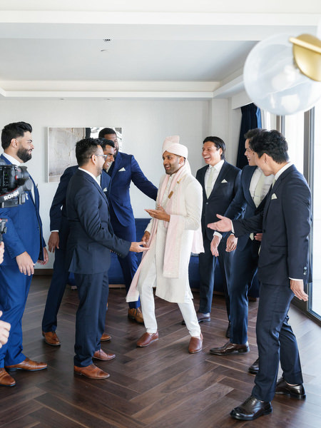 Groom making a joyful entrance surrounded by friends at his Indian destination wedding in Athens at Island Resort The Residence