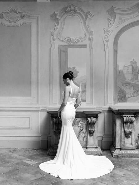 Back view of bride’s fitted gown with long train in elegant Tuscan villa interior