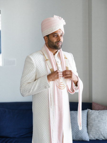 Groom adjusting traditional accessories in a modern suite before his Island Resort The Residence Indian wedding