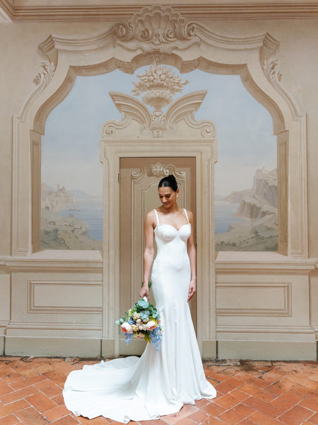Bride holding pastel bouquet in Renaissance-inspired hall during luxury Tuscany wedding at La Foce