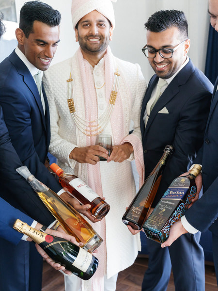 Groomsmen holding celebratory bottles before the ceremony at an Athens Riviera Indian wedding at Grand Hyatt Athens