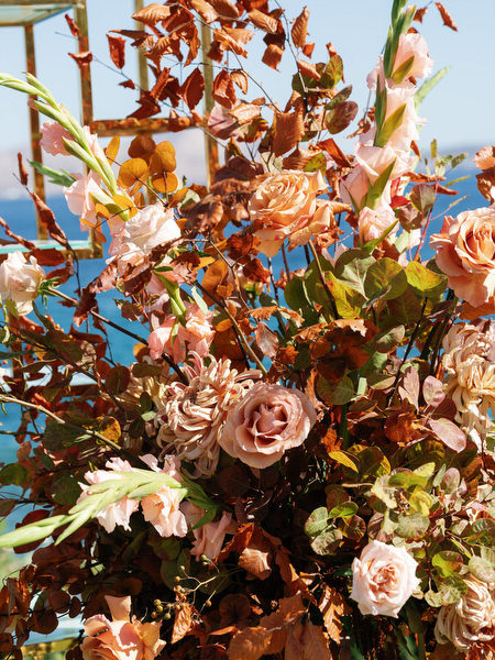Warm-toned floral centerpiece overlooking the sea at Island Resort The Residence during an Indian destination wedding in Greece