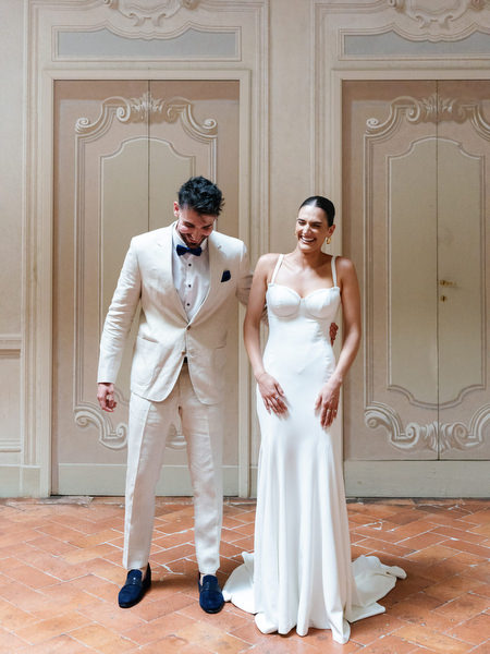 Bride and brother sharing a relaxed moment in elegant Italian villa setting during their Tuscany wedding