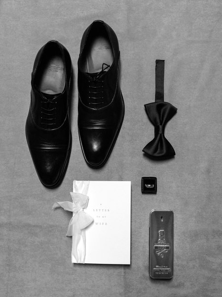 Groom accessories including black shoes, bow tie, cufflinks, and wedding invitation styled for a La Foce wedding