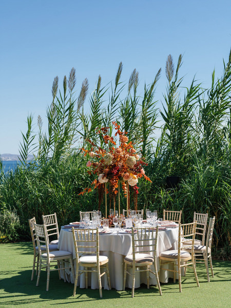 Round reception table with copper-toned florals at Island Resort the Residence during an Athens Riviera Indian wedding