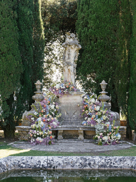 Romantic floral installation surrounding a classical statue at La Foce wedding ceremony in Tuscany