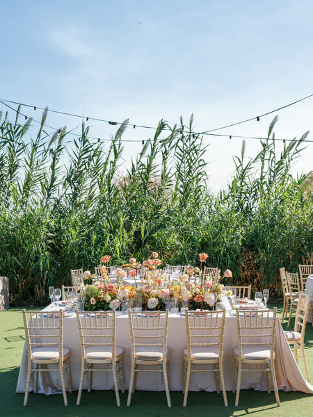 Long reception table styled with warm florals at Island Resort the Residence for an Indian destination wedding in Athens