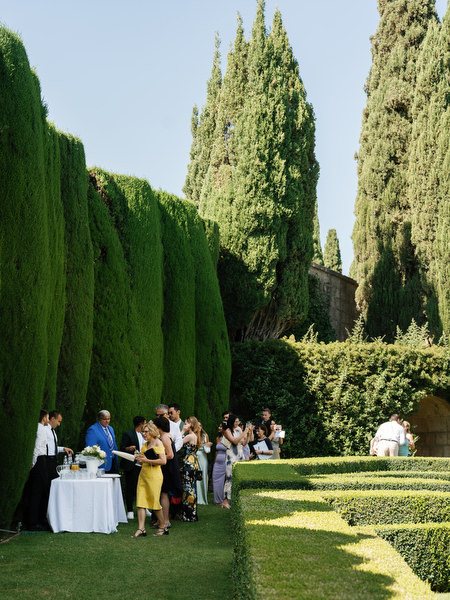 Guests enjoying pre-ceremony drinks in the cypress-lined gardens of a Tuscany destination wedding