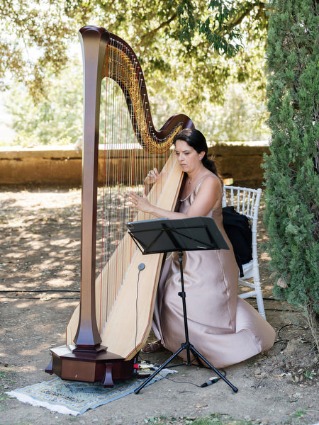 Live harpist performing during outdoor garden ceremony at La Foce estate in Tuscany