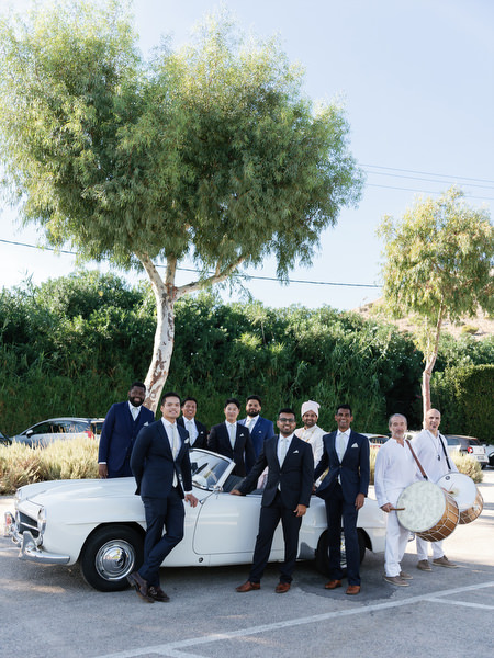 Groom and groomsmen posing with vintage car during an Athens Riviera Indian wedding at Island Resort