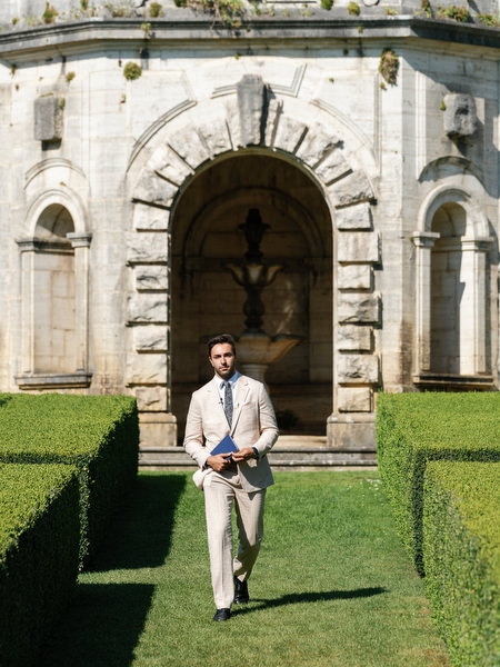 Officiant walking through manicured hedges before ceremony at La Foce wedding in Tuscany