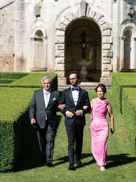 Groom escorted by his parents through the Renaissance gardens of La Foce in Tuscany