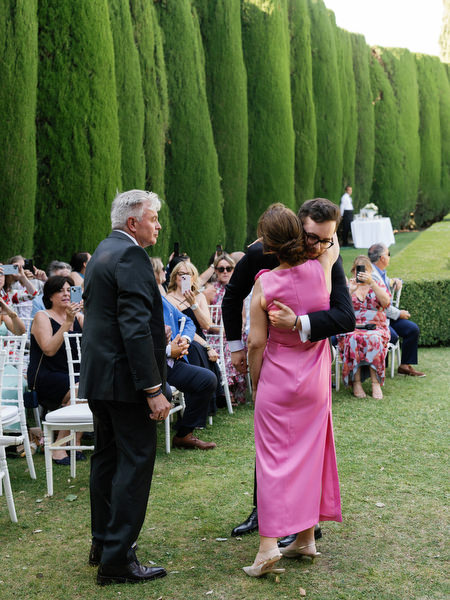 Emotional embrace between groom and his mother during outdoor garden ceremony in Tuscany
