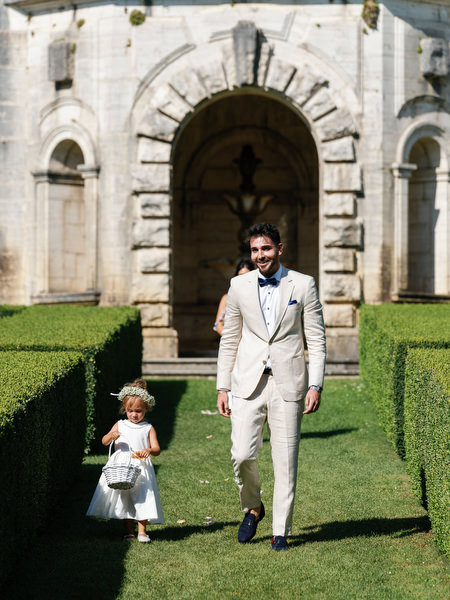 Best-man walking hand in hand with flower girl during Tuscany destination wedding ceremony