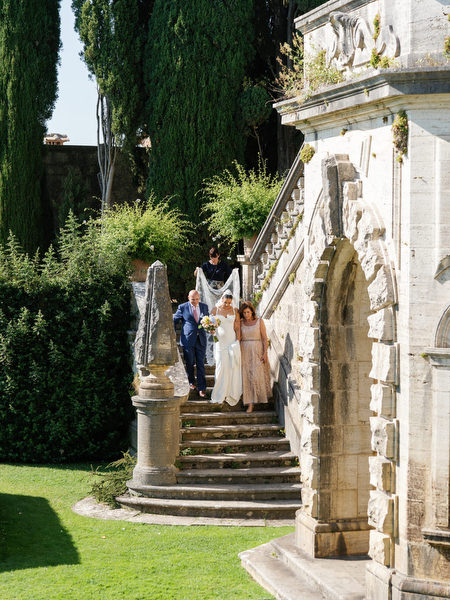 Bride escorted by his parents through the Renaissance gardens of La Foce in Tuscany