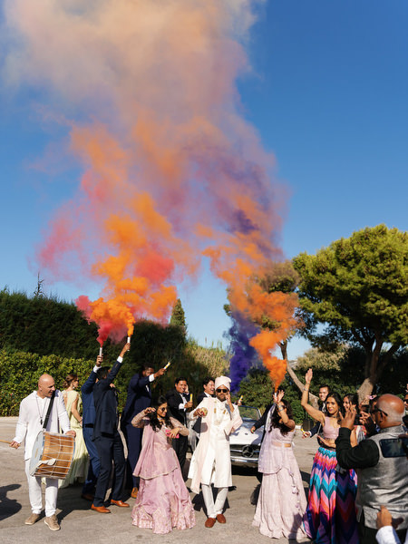 Guests celebrating with vibrant smoke during an Athens Riviera Indian wedding at Island Resort