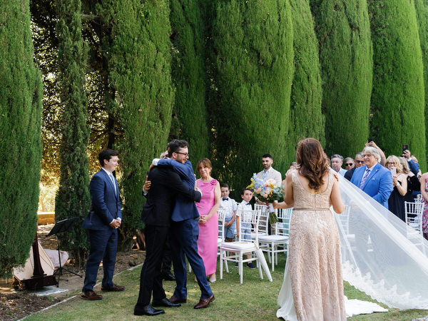 Groom embracing family moments before ceremony in the Renaissance gardens of La Foce