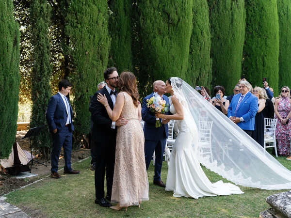 Groom embracing family moments before ceremony in the Renaissance gardens of La Foce
