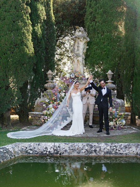 Bride and groom celebrating their first kiss beneath floral altar at La Foce in Tuscany