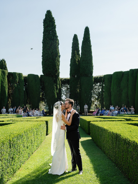 Newlyweds standing in the geometric hedge gardens at La Foce overlooking the Tuscan countryside