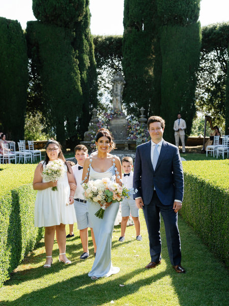 Family members walking through formal Italian gardens following the ceremony at La Foce