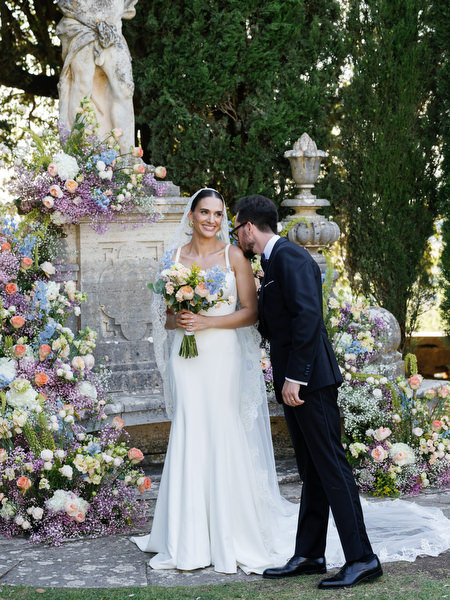 Groom leaning affectionately toward bride during post-ceremony portraits in Tuscan gardens