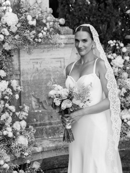 Elegant bridal portrait framed by romantic floral ceremony installation at La Foce estate