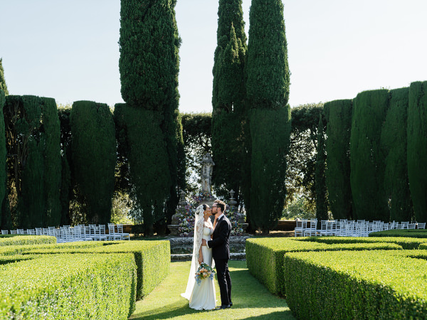 Bride and groom standing in the geometric Renaissance gardens at La Foce overlooking Tuscany