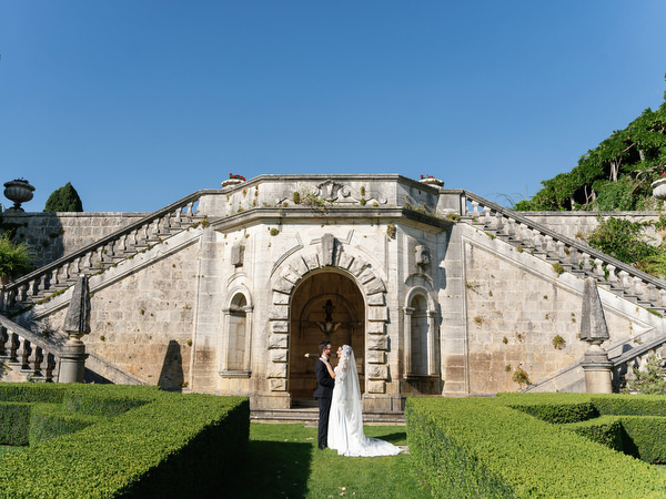 Bride framed by historic stone staircase at La Foce, an iconic wedding venue in Tuscany