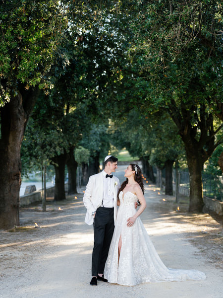 Bride and groom on cypress-lined path at Villa Corsini, luxury Florence wedding in Tuscany.
