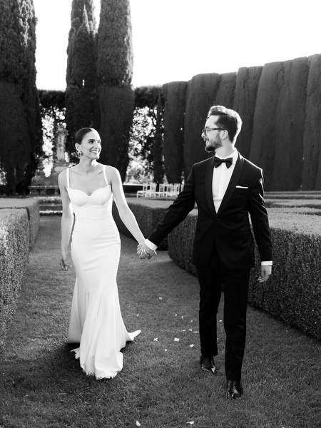 Timeless black and white portrait of newlyweds strolling through Tuscan garden pathways