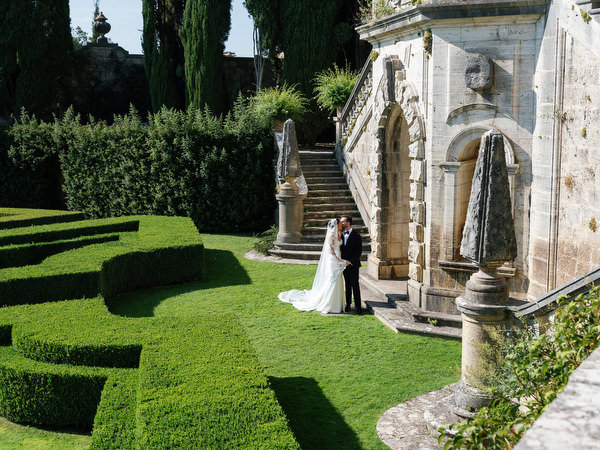 Bride and groom kissing in front of the grand stone staircase at La Foce estate in Tuscany