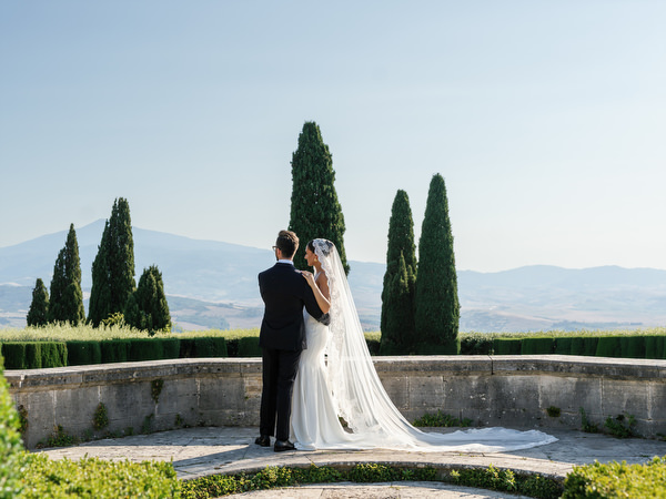 Romantic portrait of bride and groom overlooking rolling hills during luxury Tuscany wedding