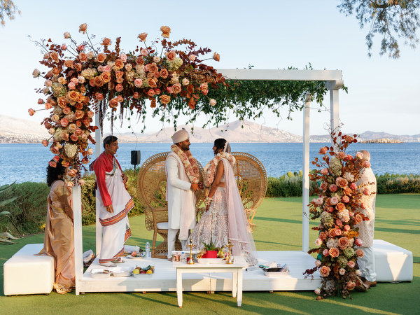 Bride and groom standing beneath peach floral canopy at Island Resort the Residence on the Athens Riviera
