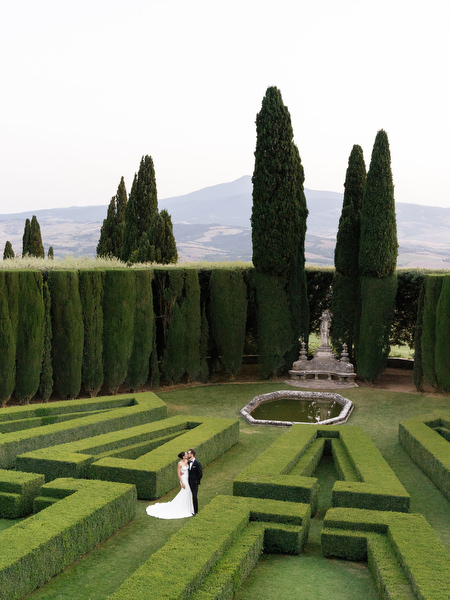 Aerial portrait of newlyweds centered within geometric hedge gardens at La Foce estate