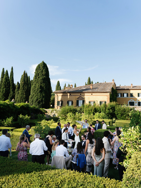 Guests gathering for cocktail hour in the gardens of La Foce during Tuscany destination wedding