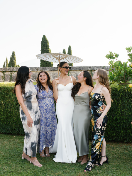 Bride posing with bridesmaids in manicured gardens at La Foce during Tuscany destination wedding