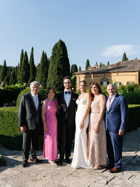 Bride and groom with family against scenic Tuscan countryside backdrop at La Foce