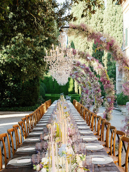 Crystal chandeliers hanging above al fresco wedding reception in Tuscan garden setting