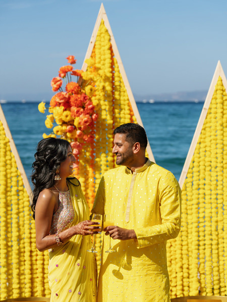 Couple standing in front of yellow Haldi ceremony decor