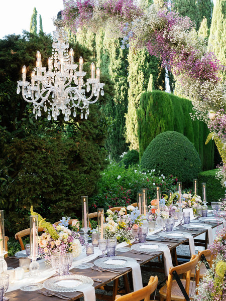 Crystal chandeliers hanging above al fresco wedding reception in Tuscan garden setting