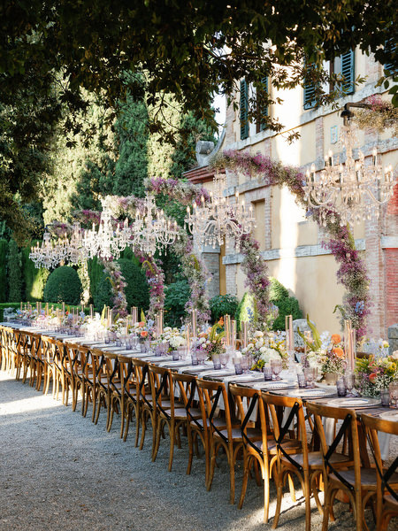 Outdoor wedding dinner in courtyard of La Foce with floral arches and candlelit tables
