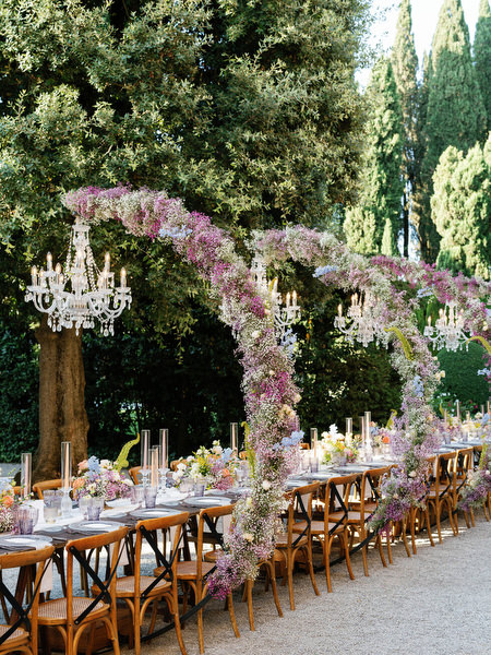 Romantic floral arches cascading over long al fresco dinner table at La Foce estate